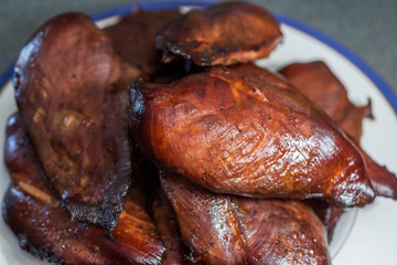 Freshly hot smoked chicken breasts or fillets piled on a plate.