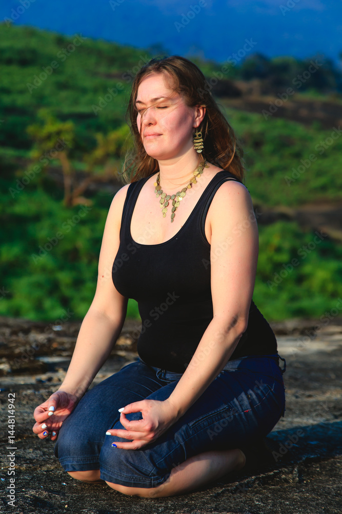 Wall mural Woman practicing yoga outdoors.