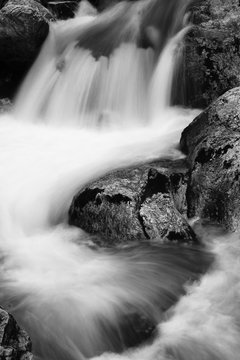 Fototapeta river rocks in smooth satin water flow of waterfall in black and white in long exposure