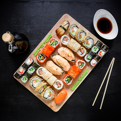 Asian food - sushi rolls, soy sauce and chopsticks on a black background. Top view. Flat lay. Restaurant food.