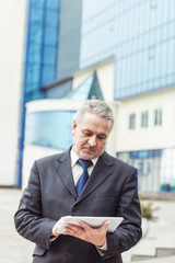 successful businessman with digital tablet on background of office building