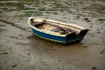 Fototapeta na wymiar Little fishing boat stranded on the wet sand