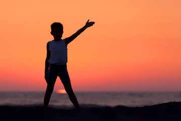 Fototapeta premium A Silhouette Of A Child Playing Near The Beach At Sunset