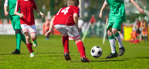 Football Soccer Match for Kids. Young Football Athletes. Coaching Youth Soccer. Children Playing Soccer Game Tournament. Boys Running and Kicking Football. Youth Soccer Coach in the Background