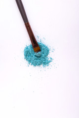 Makeup brush background with eyeshadow sprinkled on white