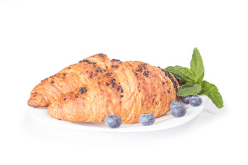 two croissants with blueberries on plate isolated on white