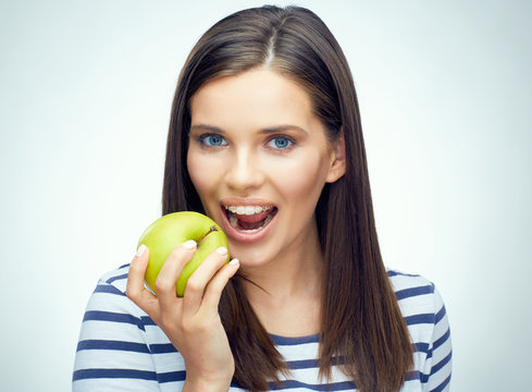 Teenager girl with dental braces bites apple.