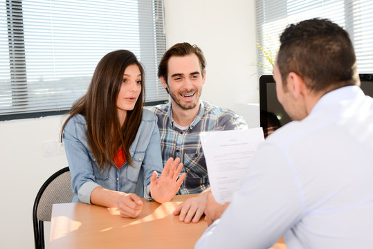happy young couple in office with businessman on business buying agreement contract signature