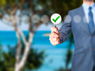 Businessman magnifying glass check mark on virtual screen.