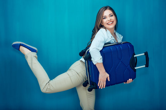 Happy young woman holding suitcase raise leg like a runner.