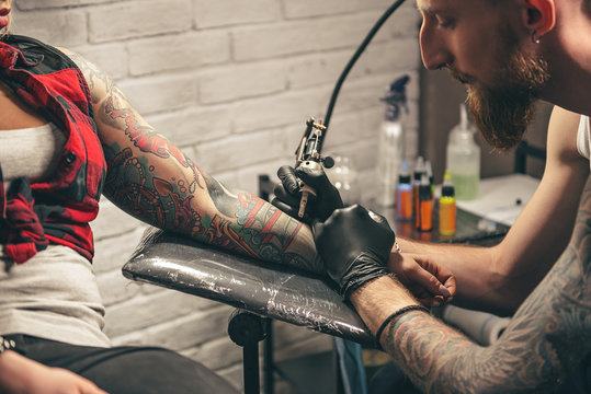 Calm man making tattoo on hand