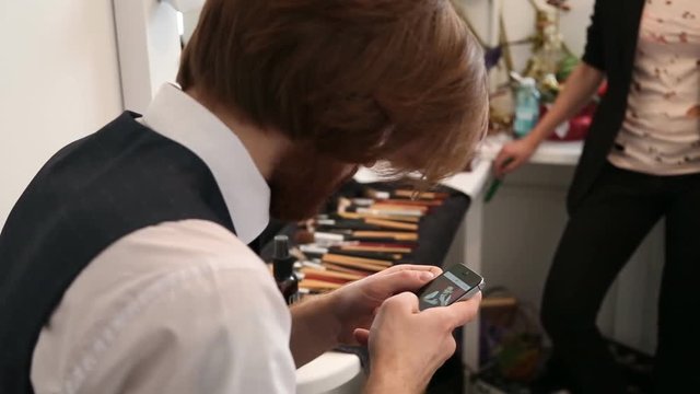 Bearded handsom young man with stylish well-trimmed using his smartphone. Elegant young handsome man looking at his smartphone
