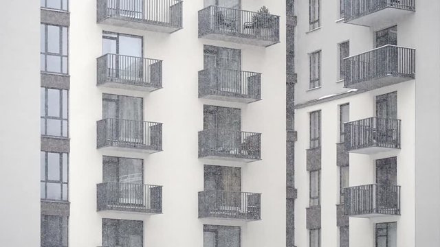 snowing in the yard of modern new building with balconies