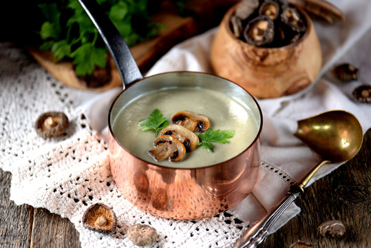 Healthy Mushroom cream soup with celery and parsley on an old wooden background. Rustic style.