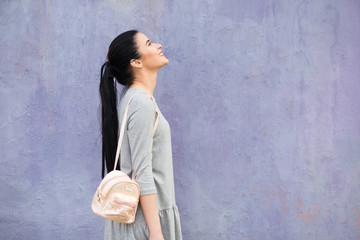 Stylish woman with bag at violet wall