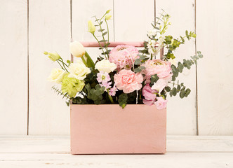 Pink wooden box with flowers roses and carnations in girl's hands