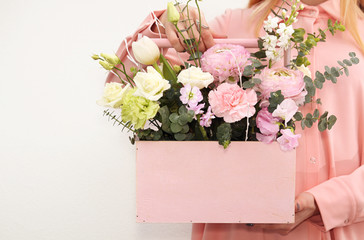 Pink wooden box with flowers roses and carnations in girl's hands