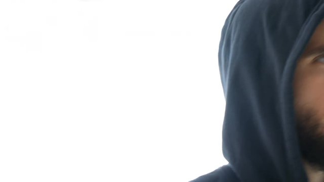 Close-up of serious thoughtful bearded man face in hoodie looking at you, studio isolated on white background.