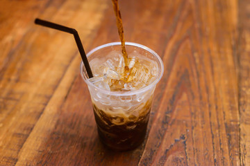 Coca cola splash or sparkling water soft drinks are pouring from bottle into glass