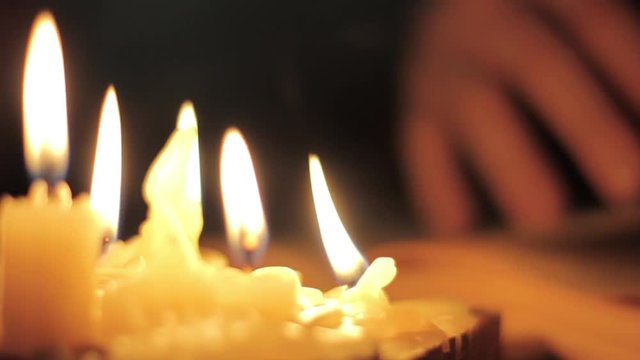 Monk reading and touching a yellow pages of old book. Light of candle in dark room