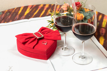 Wine glass and heart shaped box With wedding rings on the table