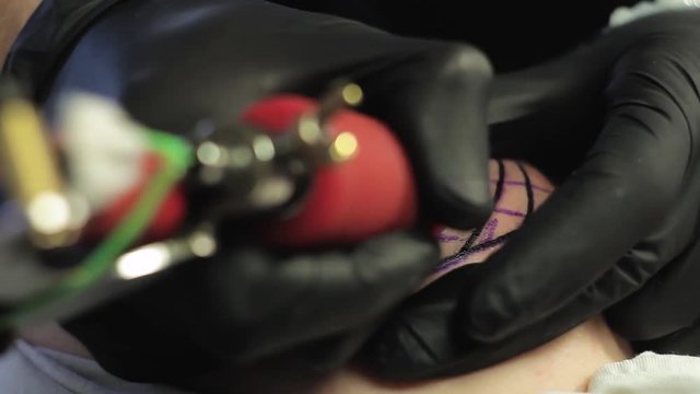The tattoo artist makes a black tattoo on man shoulder
