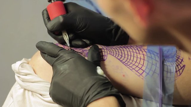 The tattoo artist makes a black tattoo on man shoulder