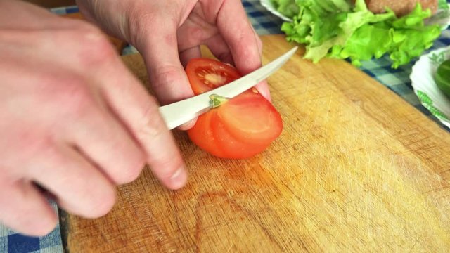Man Slicing Red Tomato on a Kitchen Table. 4K