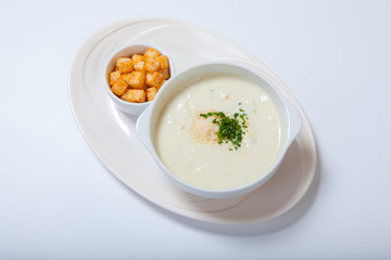 delicious creamy soup with parsley, croutons and cheese on white dish