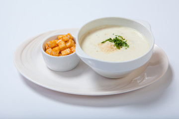 delicious creamy soup with parsley, croutons and cheese on white dish