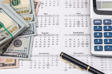 Hundred dollar bills with calendar, calculator. close up.