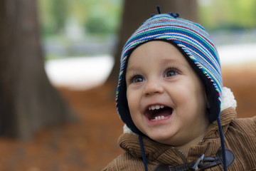 Little boy standing and smiling in autumn park
