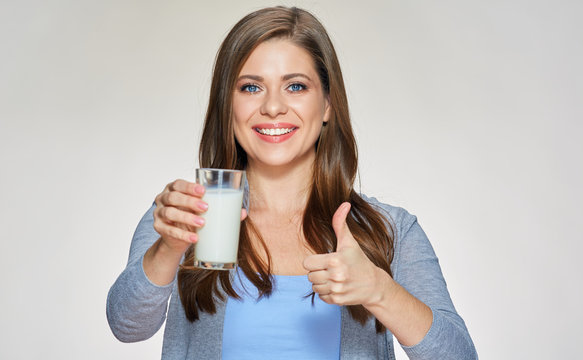 Smiling woman holding milk glass shows thumb up.