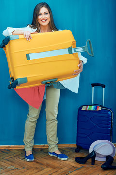 Young traveler woman holding big suitcase with clothes.