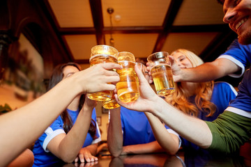 football fans clinking beer glasses at sport bar