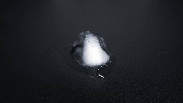Time Lapse of Melting Ice Cube on black reflective background. 4K 