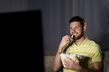 happy man with popcorn watching tv at night