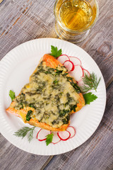 Baked salmon with spinach and cheese. Fish on white plate.