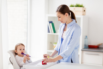 mother and baby with spoon eating puree at home