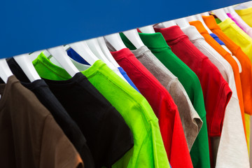 Bright colored T-shirts on hangers