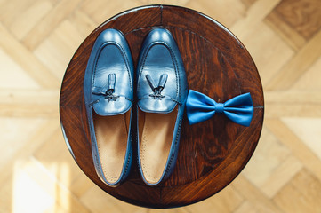 Blue shoes and bow tie on a wooden round stool. Accessory for formal dress. Symbol of elegance and fashion for men.