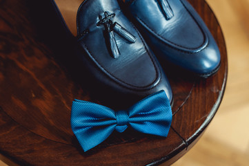 Blue shoes and bow tie on a wooden round stool. Accessory for formal dress. Symbol of elegance and fashion for men.