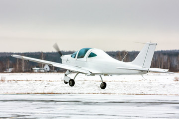 Fototapeta na wymiar Takeoff the small sport airplane at winter airfield