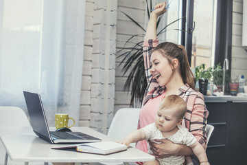 Family mother works with a laptop via the Internet and the baby happy together at home