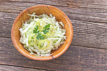 Sliced young cabbage salad in bamboo bowl on table
