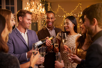 Friends Open Champagne As They Celebrate At Party Together