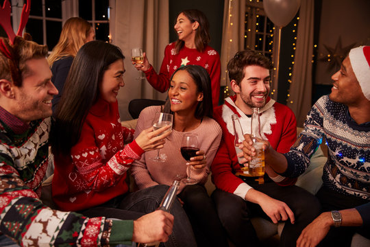 Friends In Festive Jumpers Celebrate At Christmas Party