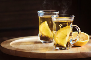 two cups of tea and lemon slices closeup on wooden background with place for your text, hot healthy drinks