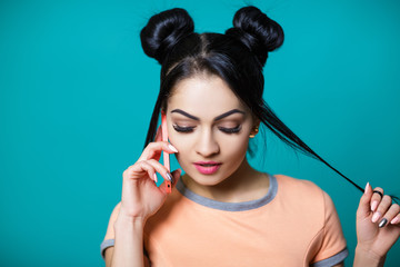 beautiful brunette woman with hair mouse smiling and talking on phone on blue background