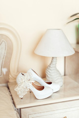 white wedding shoes with heels on a pedestal next to a table lamp. All in bright colors